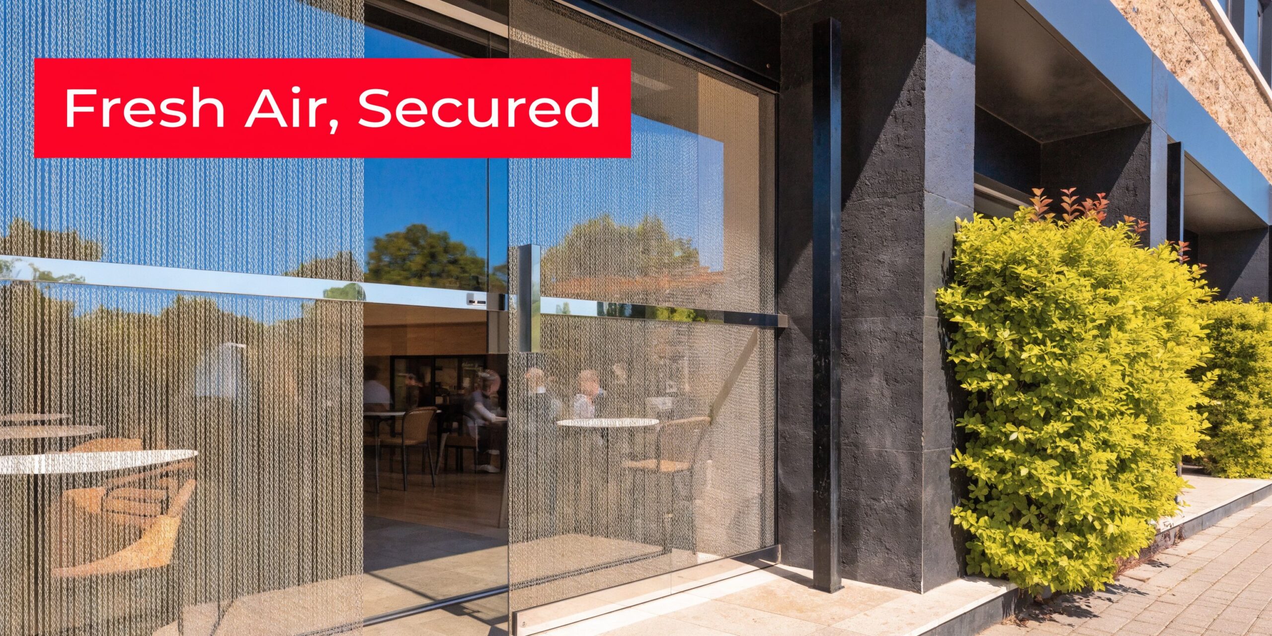 Insect Screens A commercial building entrance featuring metal chain curtains installed over large glass doors and windows for ventilation.