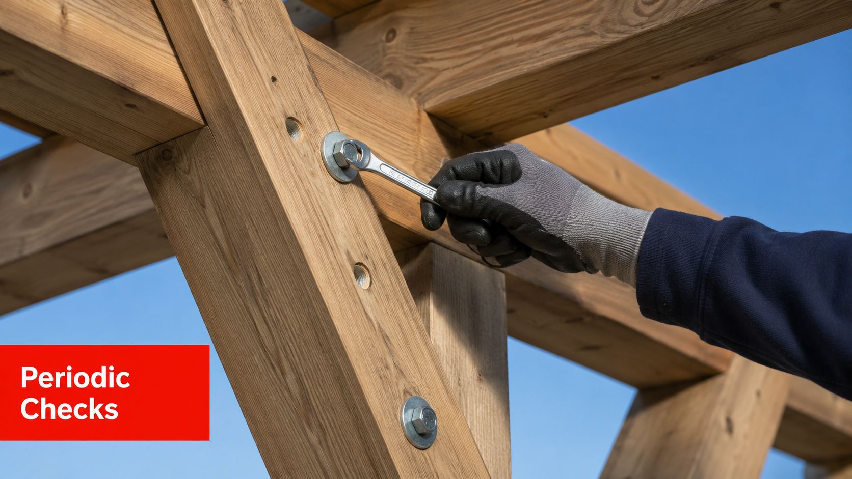 A gloved hand uses a wrench to tighten a bolt on a heavy timber frame construction project.